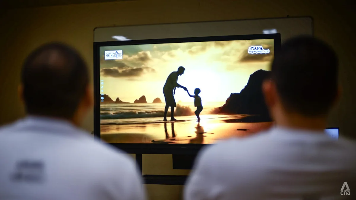 Dua narapidana menyaksikan tayangan video bersama dalam acara Hari Ayah di Penjara Changi