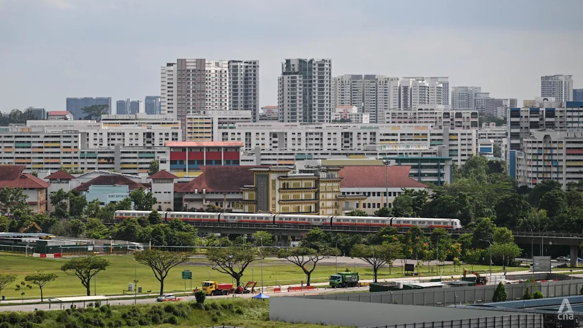 Kereta MRT melintas di dekat kawasan perumahan publik HDB di Singapura