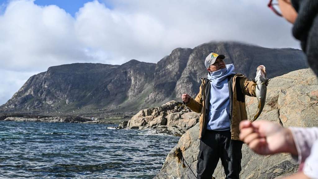 Seorang migran asal Filipina bersama anaknya memegang ikan hasil tangkapan di fiord Sisimiut Greenland
