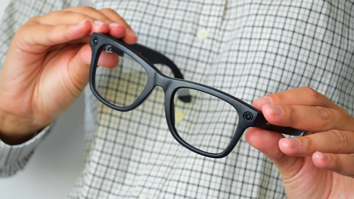 Seseorang memegang kacamata pintar atau smart glasses yang dilengkapi kamera tersembunyi di bagian bingkai.